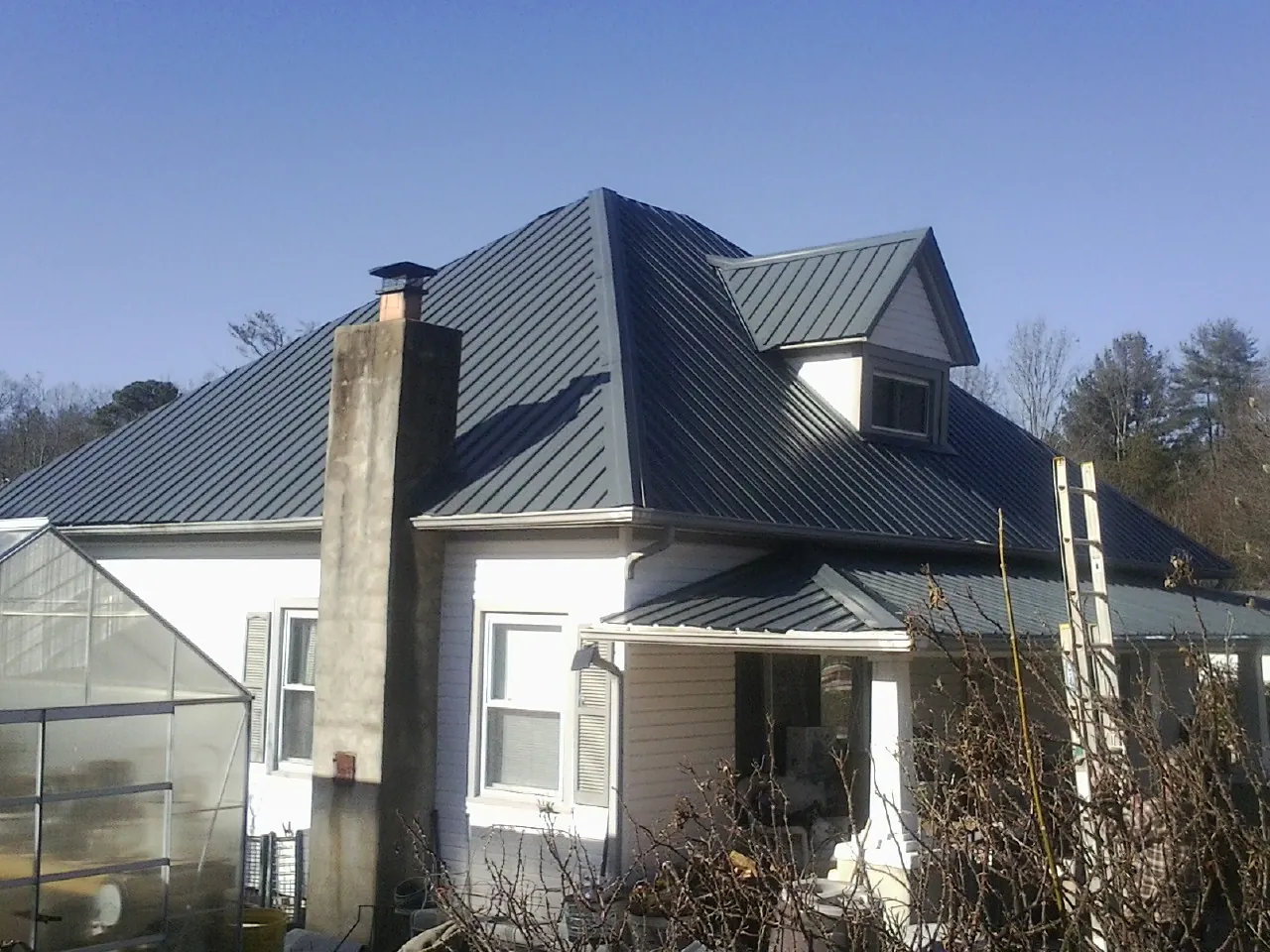 Dark blue standing seam metal roof on a white farmhouse with dormer — Slate & Tile Roof Repair by Roofing Brothers in Hilliard