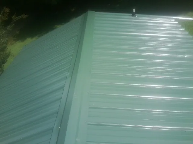 New green metal panels meeting at the ridge of a roof — Flat Roof Repair work by our crew in Hilliard
