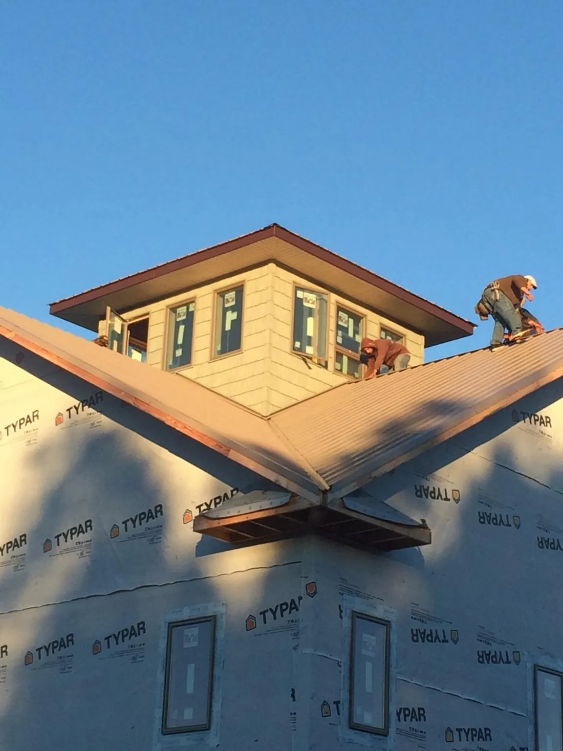 Roofers working around a rooftop cupola on a new metal roof at sunset — Roof Waterproofing in Hilliard by Roofing Brothers